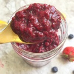 Close spoon shot of strawberry blueberry compote in a jar