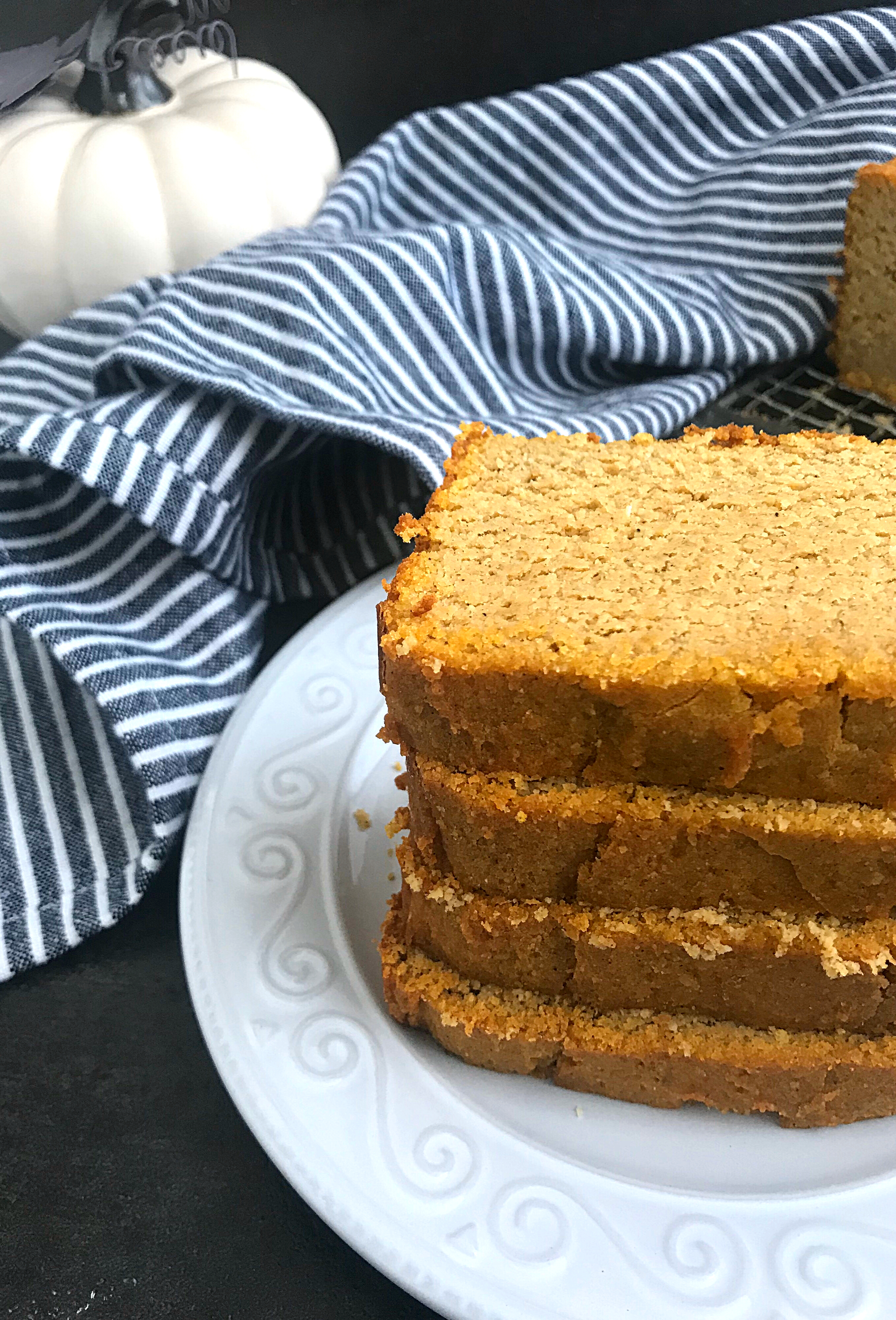 keto Pumpkin bread slices in a plate with a dish cloth and decorative pumpkin at the background