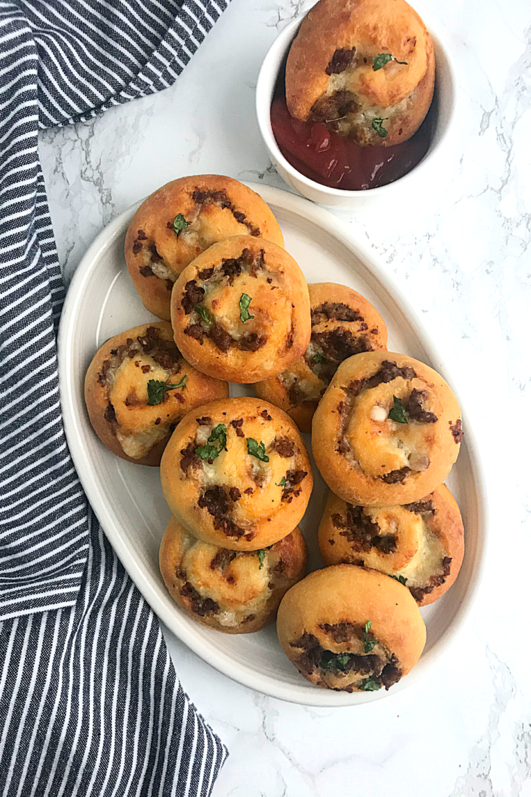 keto pizza rolls in a plate with a small bowl of marinara sauce by the side
