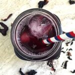 Top view of sugar free sorrel drink with a straw inserted and some ice cubes.